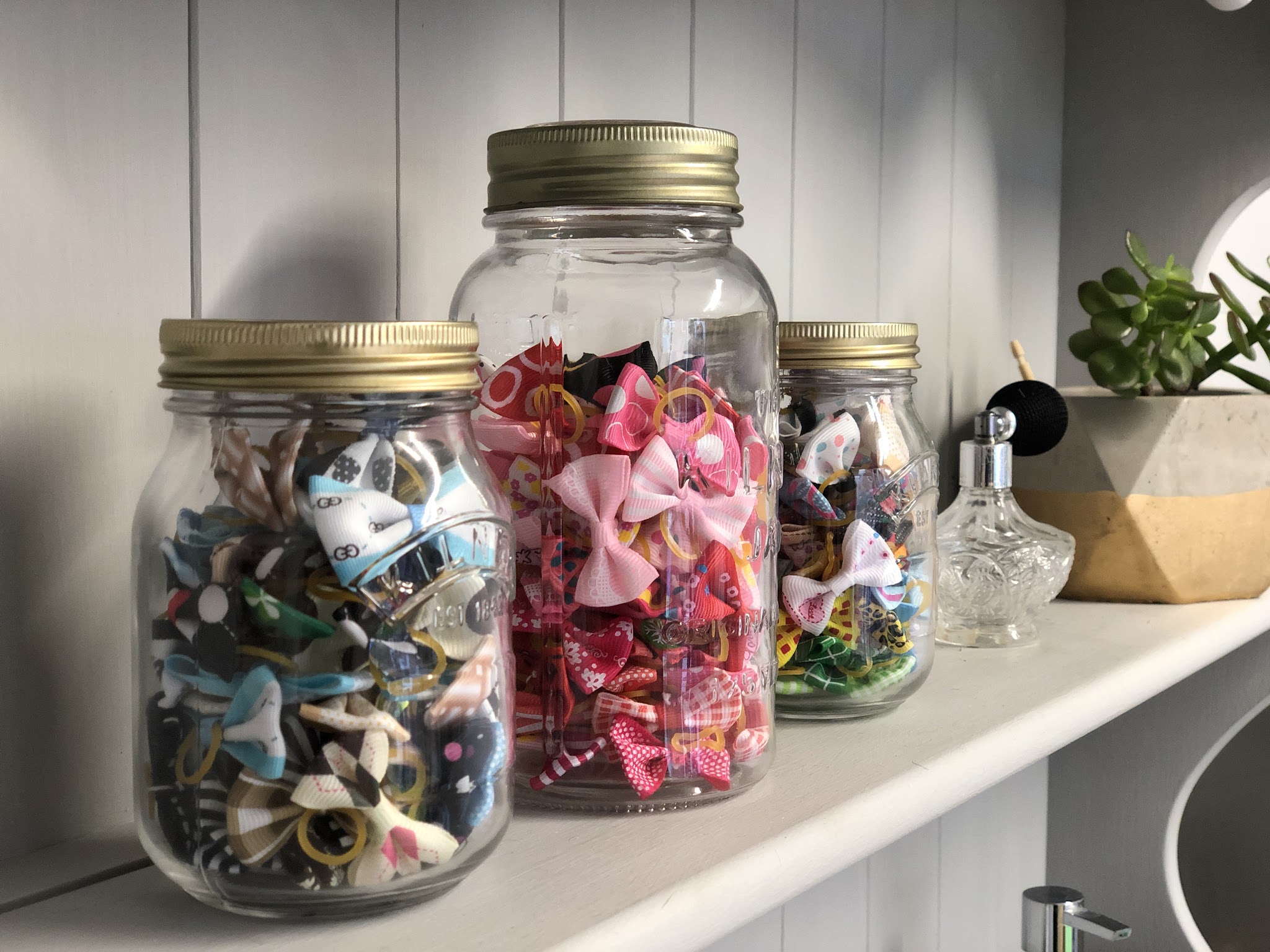 Glass jars filled with colourful dog bows on a shelf
